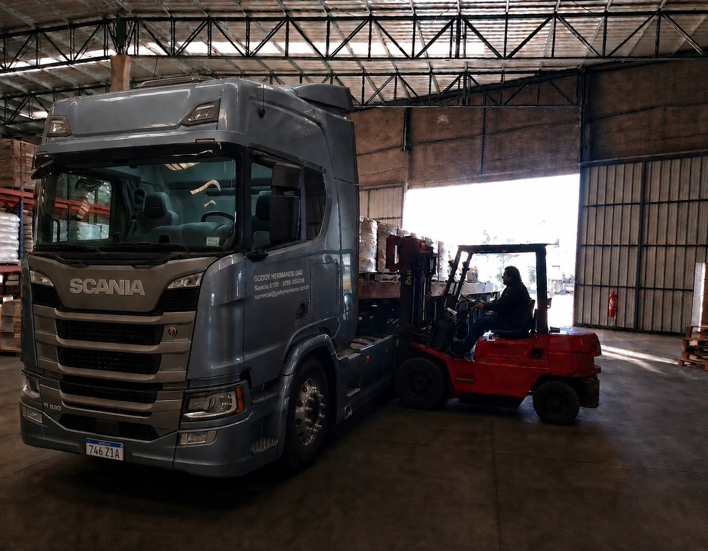 Camión Scania de Godoy Hermanos cargando mercadería con un autoelevador en un depósito